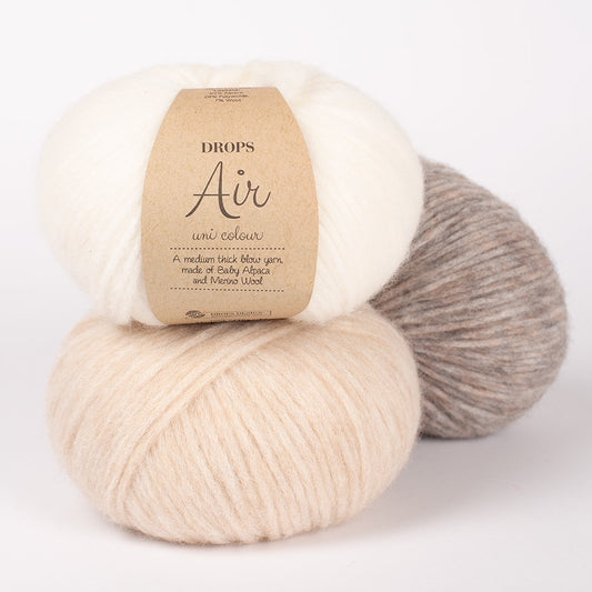 Three skeins of Drops Air alpaca yarn in natural shades, showcasing the soft texture of the alpaca and merino wool blend.